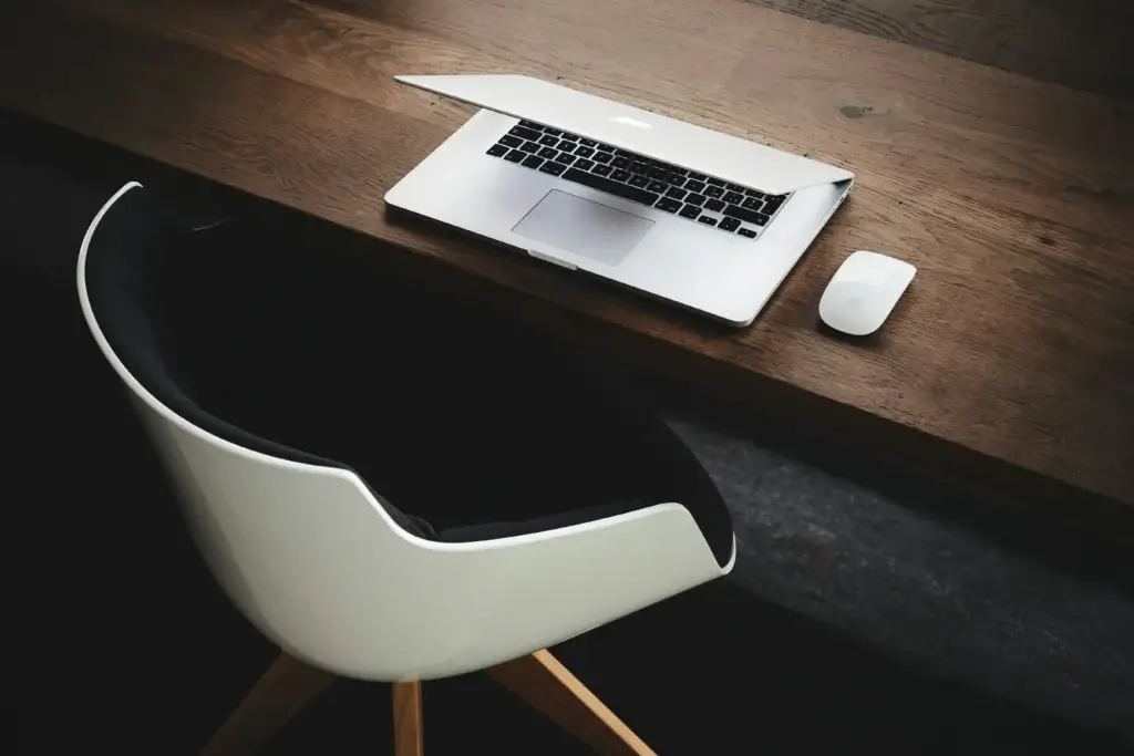 Laptop and mouse on wooden desk in minimalist workspace for work management